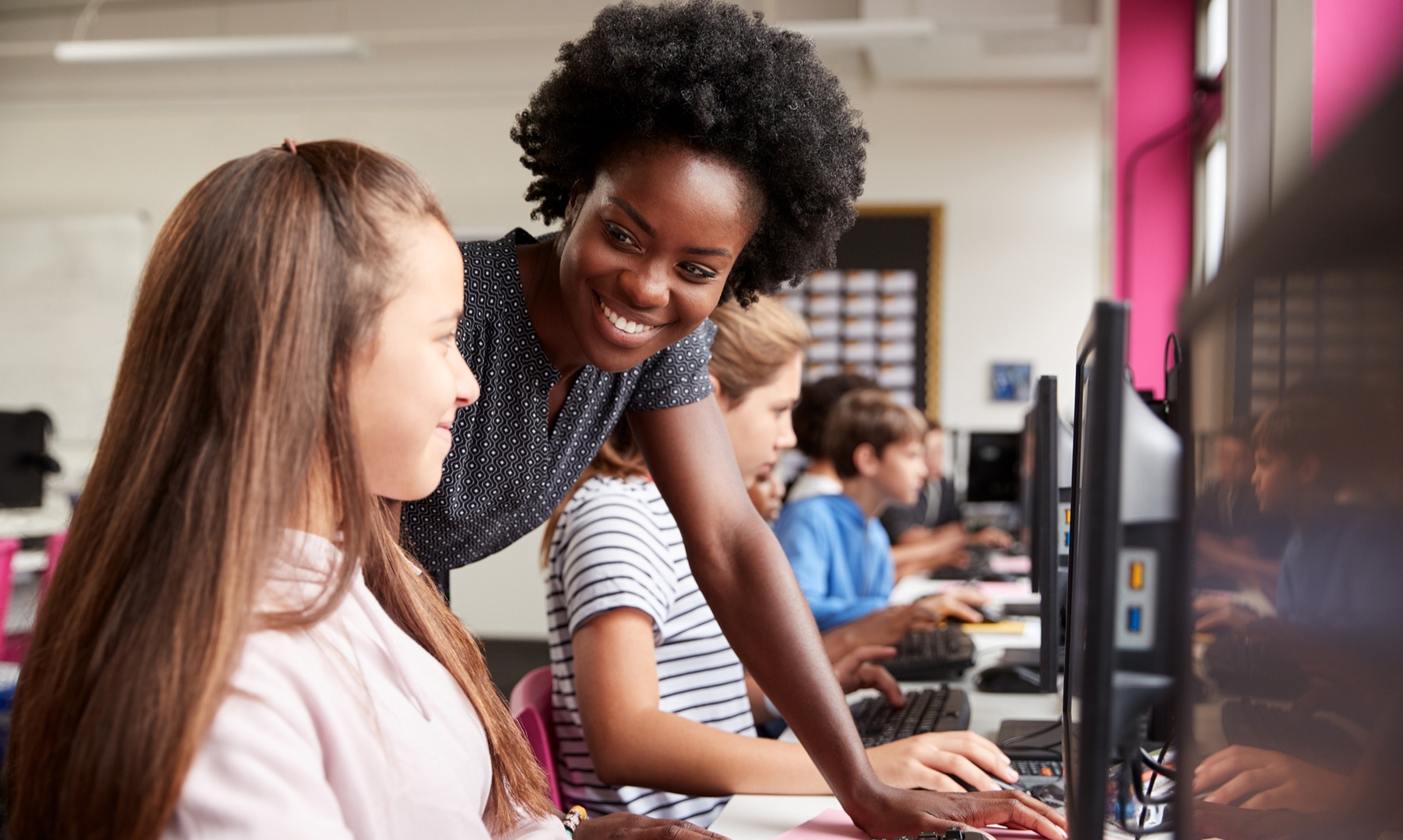 Docent begeleidt leerlingen achter computers